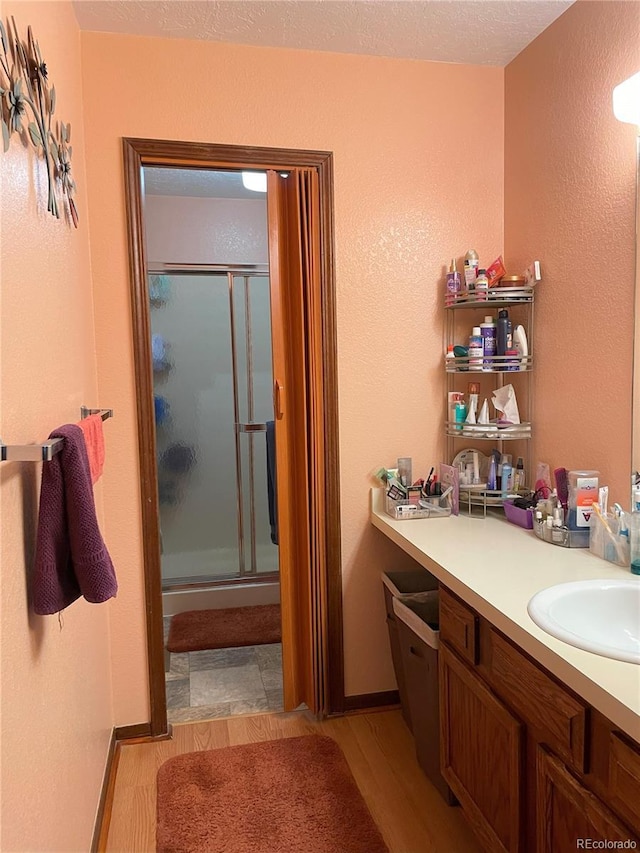 bathroom with vanity, a shower with door, hardwood / wood-style floors, and a textured ceiling