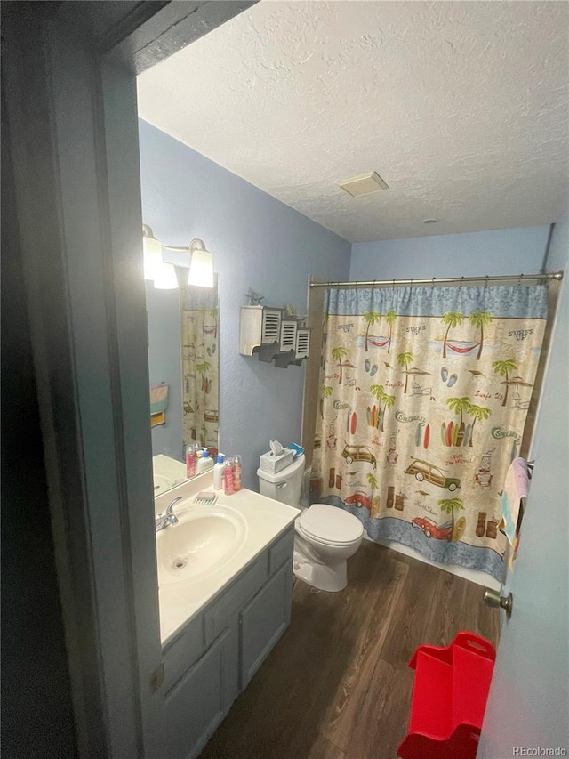 full bathroom with a shower with shower curtain, toilet, a textured ceiling, vanity, and wood finished floors