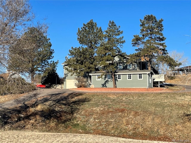 view of front of property with a wooden deck, a garage, and a front lawn