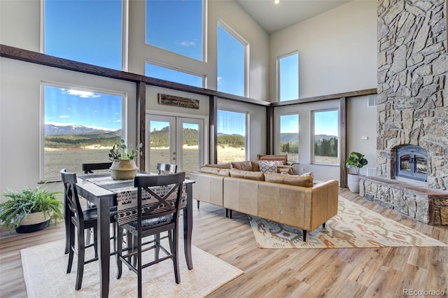 10617 County Rd 1, Florissant, CO 80816 - dining room featuring french doors, a stone fireplace, wood finished floors, a towering ceiling, and plenty of natural light