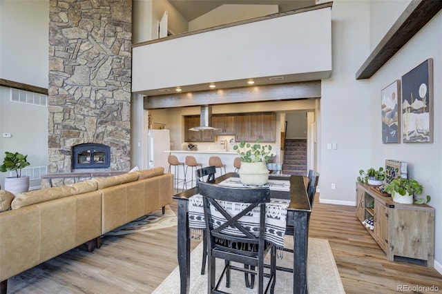 10617 County Rd 1, Florissant, CO 80816 - dining room featuring light wood-style flooring, baseboards, a high ceiling, and a stone fireplace