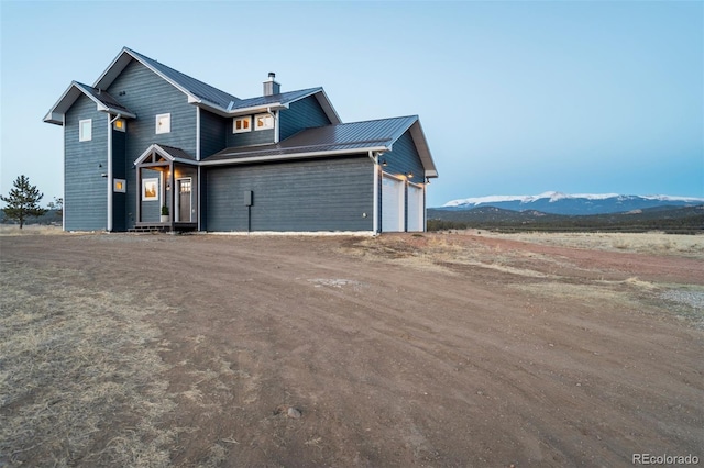 10617 County Rd 1, Florissant, CO 80816 - view of front of property with a chimney, metal roof, dirt driveway, an attached garage, and a standing seam roof