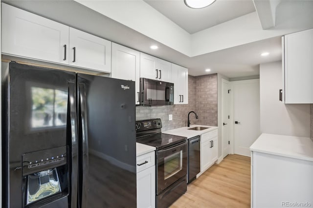 kitchen featuring decorative backsplash, sink, black appliances, light hardwood / wood-style flooring, and white cabinets