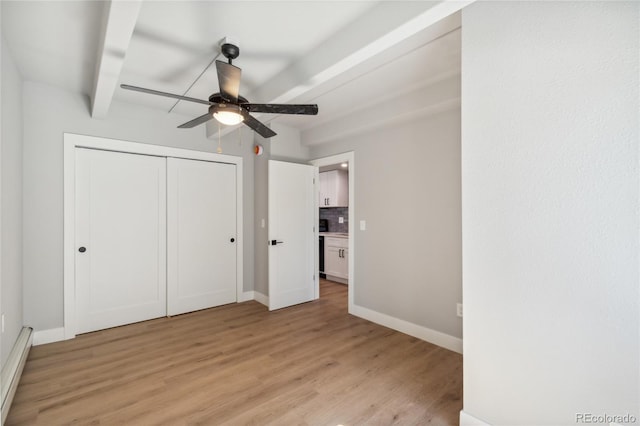 unfurnished bedroom featuring ceiling fan, light wood-type flooring, baseboard heating, beamed ceiling, and a closet