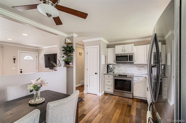 9146 W 89th Ct, Broomfield, CO 80021 - kitchen featuring appliances with stainless steel finishes, white cabinetry, hardwood / wood-style floors, decorative backsplash, and ceiling fan