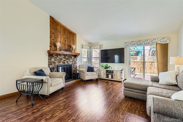 living room with a wealth of natural light, dark wood-style floors, a stone fireplace, and lofted ceiling