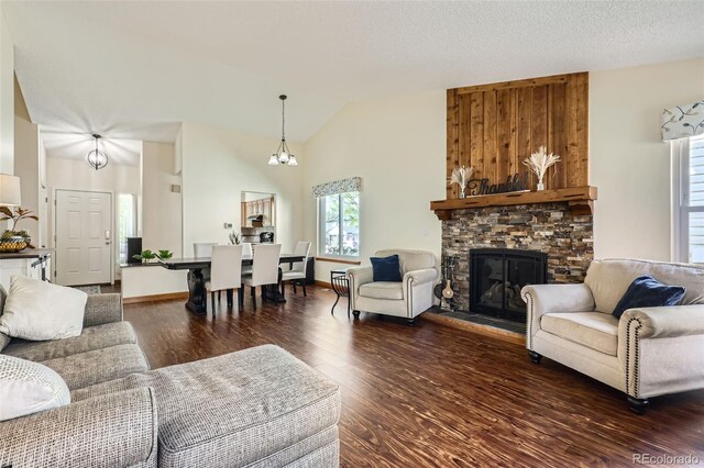 living room with high vaulted ceiling, a stone fireplace, and wood finished floors