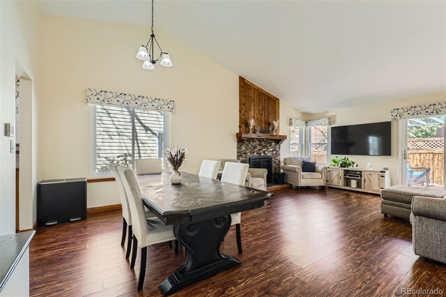 dining room with a chandelier, high vaulted ceiling, dark wood finished floors, and a fireplace