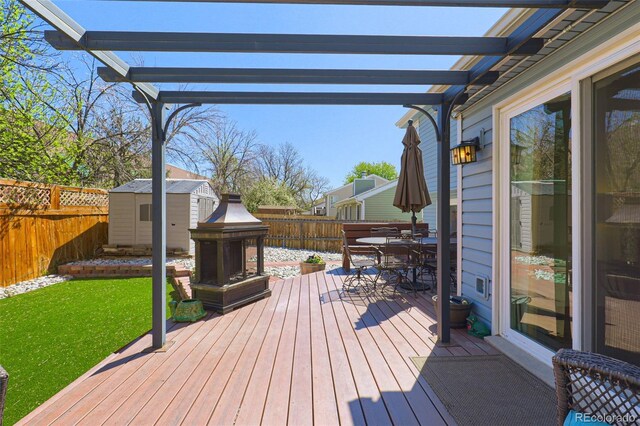 wooden deck featuring a pergola, outdoor dining area, a fenced backyard, and a storage unit