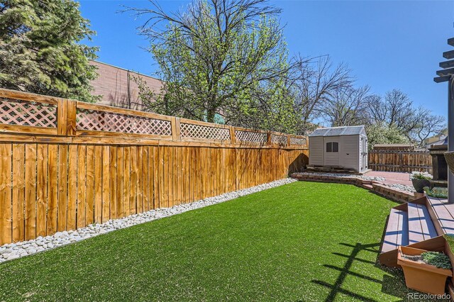 view of yard featuring an outbuilding, a fenced backyard, and a shed