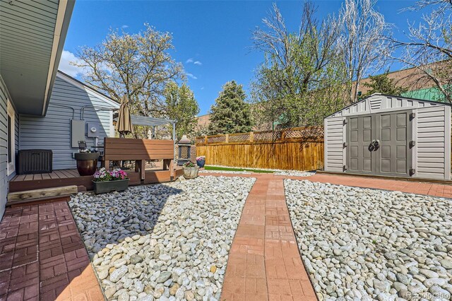view of patio with fence, a storage unit, an outdoor structure, and a wooden deck