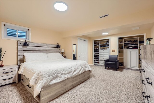 bedroom featuring multiple closets, visible vents, and light colored carpet