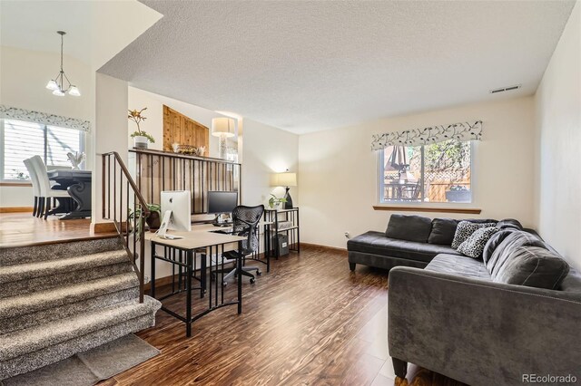 living room with visible vents, wood finished floors, baseboards, stairway, and a textured ceiling