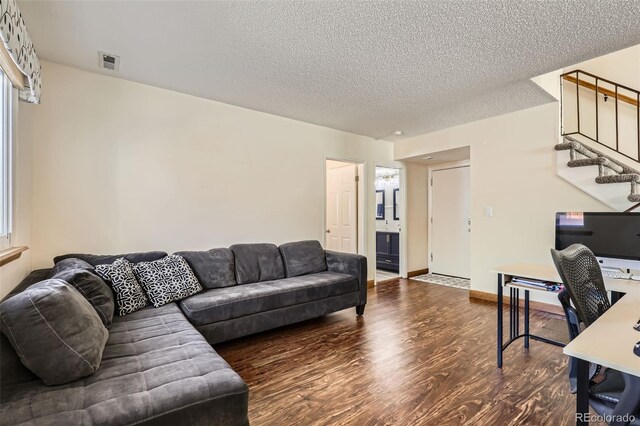 living room with stairs, a textured ceiling, visible vents, and wood finished floors