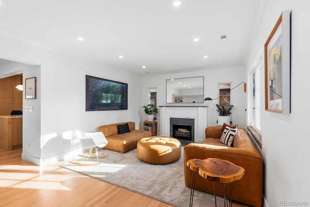 living area with recessed lighting, wood finished floors, visible vents, a high end fireplace, and ornamental molding