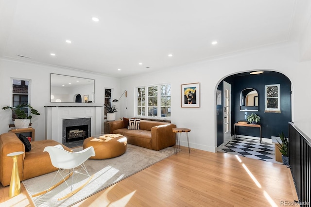 living area featuring arched walkways, light wood finished floors, a fireplace, and recessed lighting