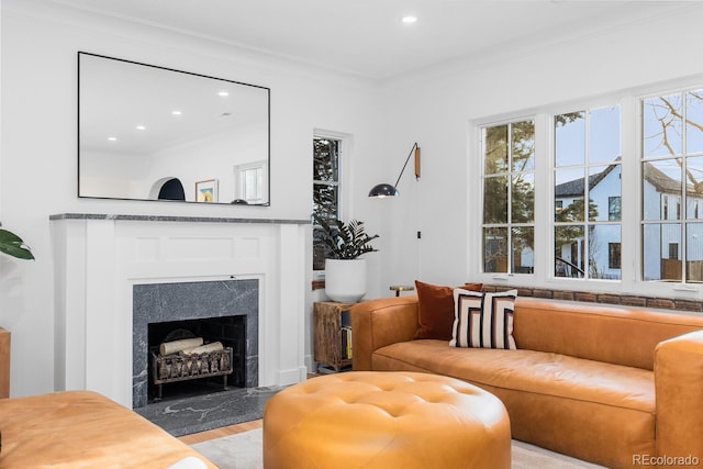 living area with a fireplace with raised hearth, light wood finished floors, recessed lighting, and crown molding