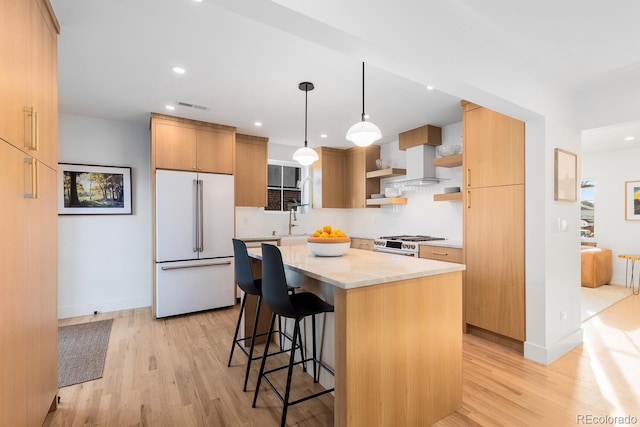 kitchen featuring white appliances, light wood-style flooring, a kitchen breakfast bar, wall chimney range hood, and open shelves