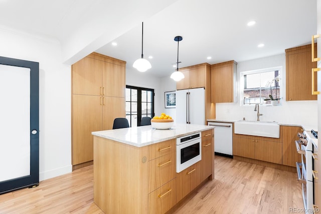 kitchen with a wealth of natural light, light wood finished floors, a sink, and high quality appliances