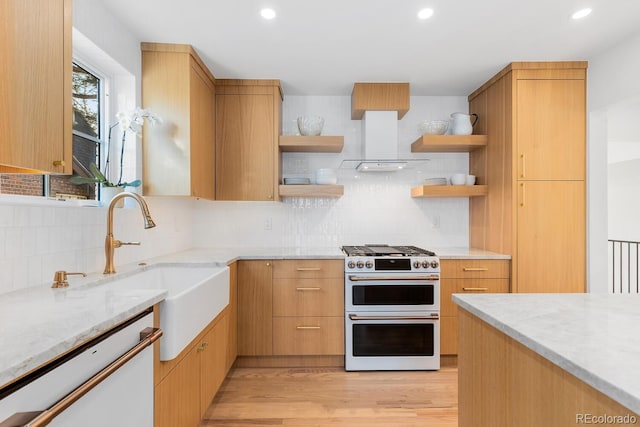 kitchen with white appliances, backsplash, wall chimney range hood, open shelves, and a sink