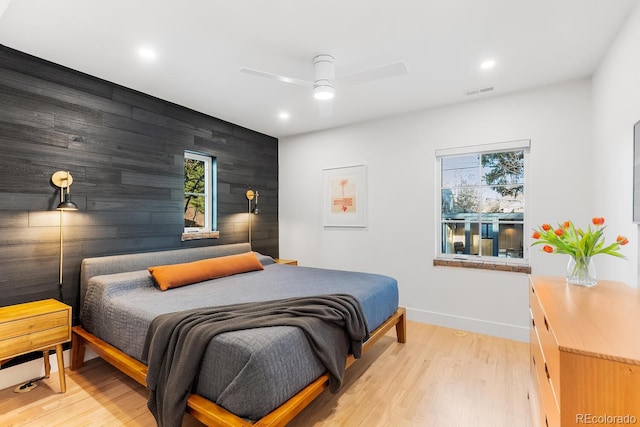 bedroom with visible vents, an accent wall, light wood-style floors, ceiling fan, and baseboards