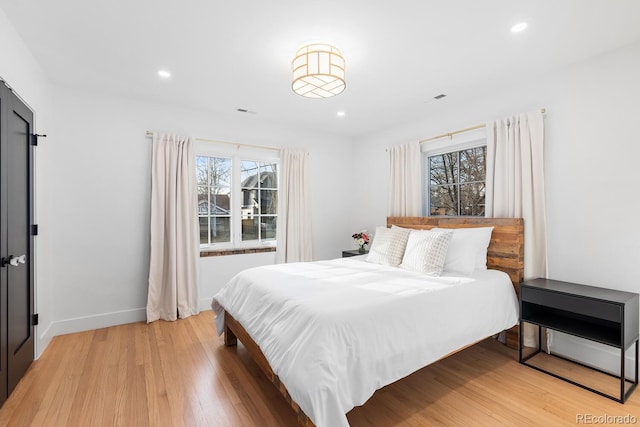 bedroom with light wood-type flooring, multiple windows, baseboards, and recessed lighting