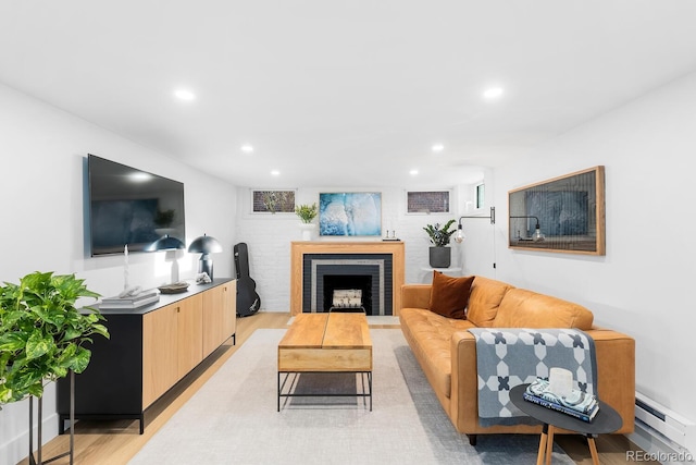 living area featuring recessed lighting, a fireplace, a baseboard radiator, and light wood-style floors