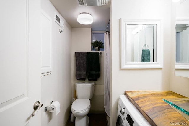 bathroom featuring washer / clothes dryer and toilet