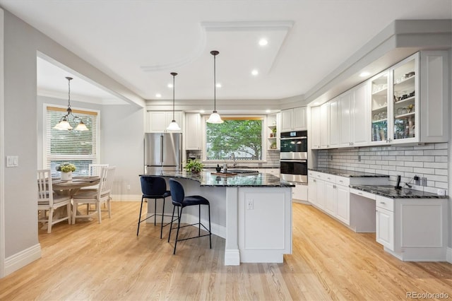 4059 Nevis St, Boulder, CO 80301 - kitchen with stainless steel appliances, white cabinetry, decorative backsplash, a kitchen breakfast bar, and dark stone counters