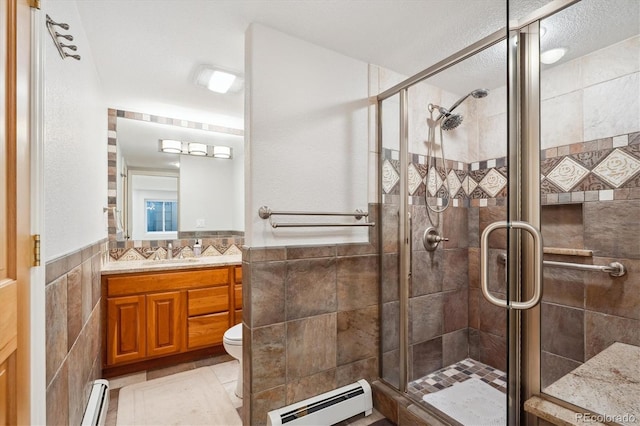 4059 Nevis St, Boulder, CO 80301 - bathroom with a baseboard heating unit, tile walls, vanity, a shower stall, and toilet