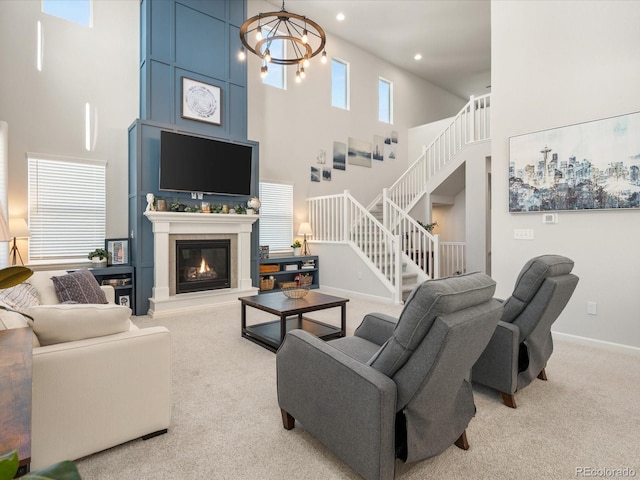 living room featuring a chandelier, a glass covered fireplace, light carpet, and stairs