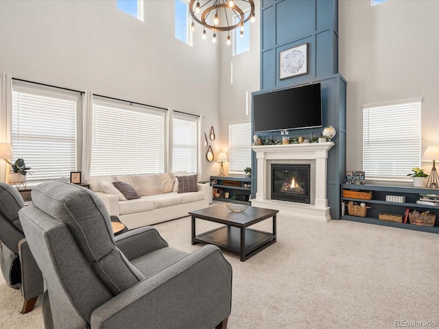 living area with an inviting chandelier, carpet, and a glass covered fireplace