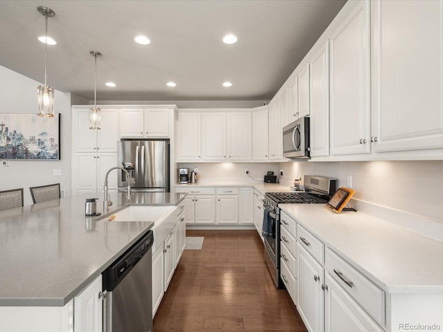 kitchen featuring a sink, white cabinetry, appliances with stainless steel finishes, an island with sink, and pendant lighting