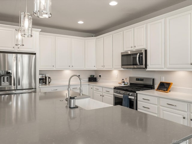 kitchen featuring white cabinets, decorative light fixtures, stainless steel appliances, a sink, and recessed lighting