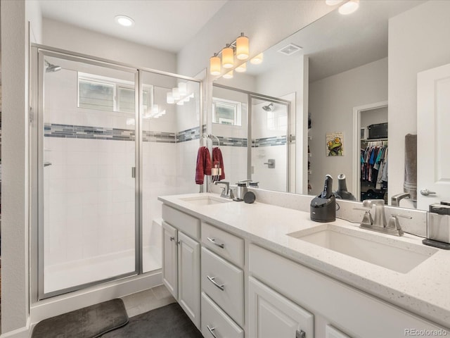 bathroom with visible vents, a sink, a spacious closet, and double vanity