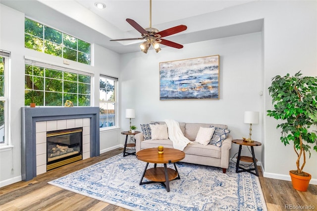 8199 Welby Rd Unit 4106, Denver, CO 80229 - living area featuring wood finished floors, a ceiling fan, a fireplace, and a tray ceiling