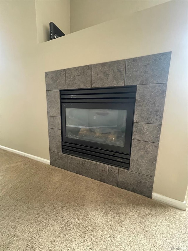 interior details featuring a tiled fireplace and carpet flooring