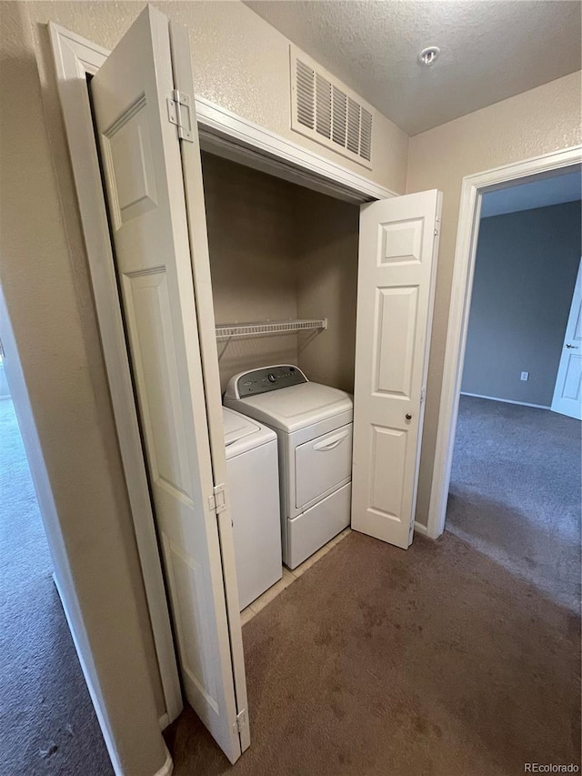 laundry area with a textured ceiling, washing machine and dryer, and dark colored carpet