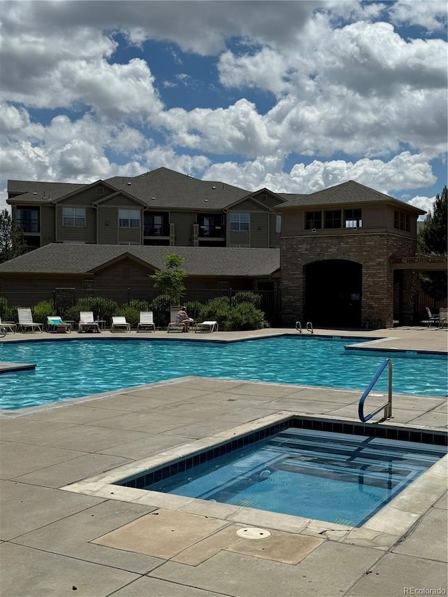 view of swimming pool with a patio area and a community hot tub