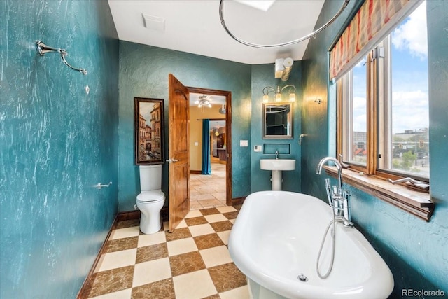2150 Curtis St, Denver, CO 80205 - full bathroom with a soaking tub, tile patterned floors, toilet, a sink, and baseboards