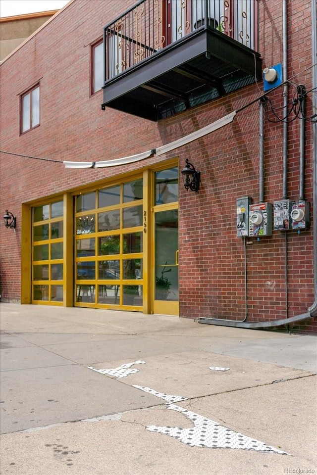 2150 Curtis St, Denver, CO 80205 - view of exterior entry with a balcony, brick siding, and uncovered parking