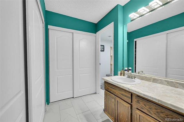 14300 E Marina Dr Unit 109, Aurora, CO 80014 - bathroom with vanity, marble finish floors, and a textured ceiling