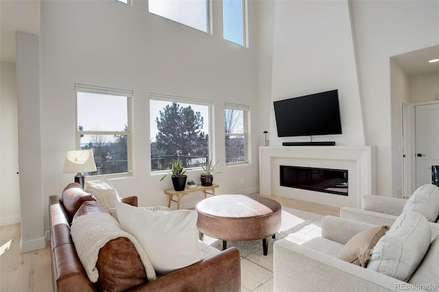 living room featuring a towering ceiling and light wood-type flooring