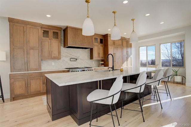 kitchen with hanging light fixtures, sink, range, and a spacious island