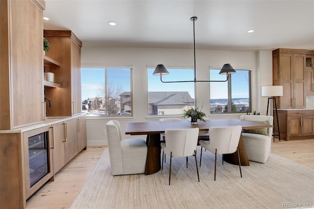 dining space with sink, light hardwood / wood-style flooring, and beverage cooler