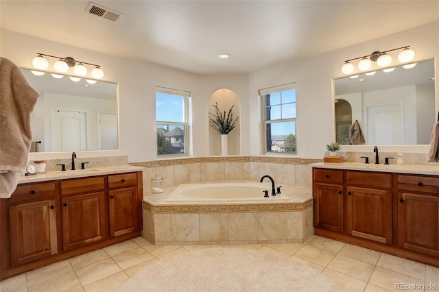 bathroom with vanity, tile patterned flooring, and tiled tub