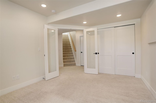 unfurnished bedroom featuring a closet, light colored carpet, and french doors