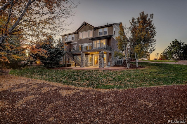 back house at dusk with a patio and a yard