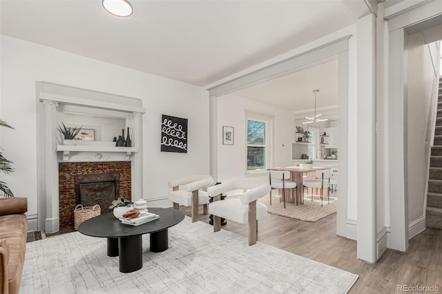 living area featuring stairs, a fireplace with flush hearth, and light wood-style floors