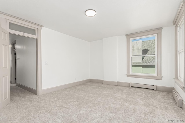 empty room featuring a baseboard heating unit, baseboards, light carpet, and baseboard heating